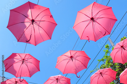 Bright red umbrellas hanging in the air with clear blue sky background
