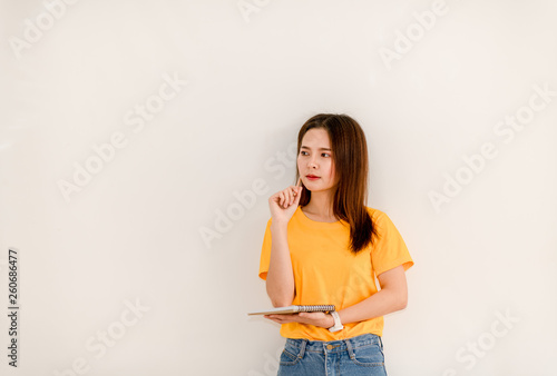 The girl standing holding writing in a notepad while standing on a white background