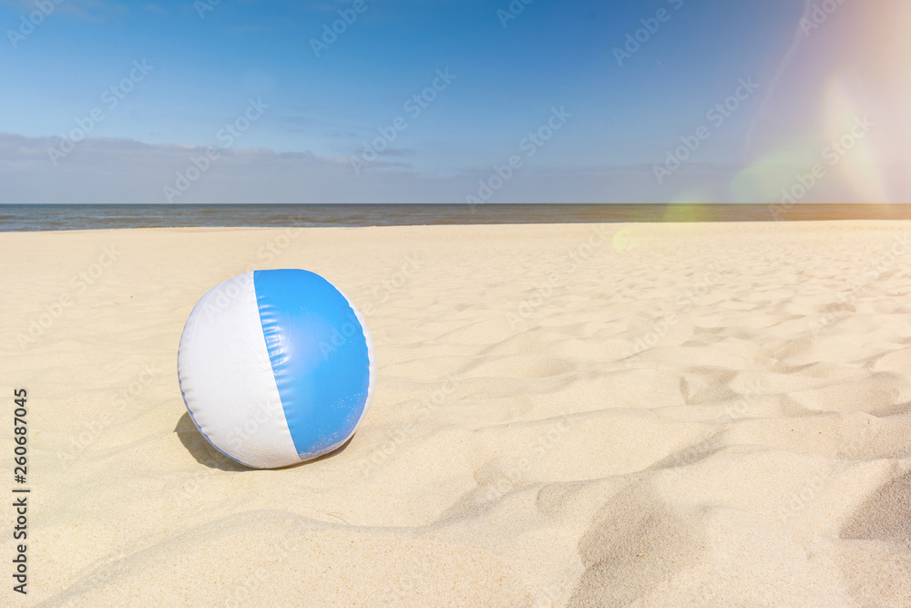Aufblasbarer Wasserball liegt am Strand im Sand mit Lens-Flare