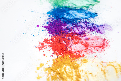 Bright eye shadows in different colors of the rainbow, scattered on a white background.