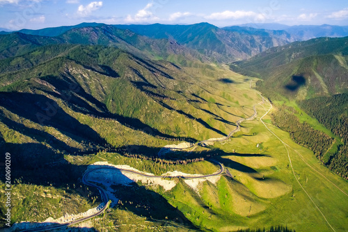 Aerial shot of the road among the green meadows and mountains © Vasily