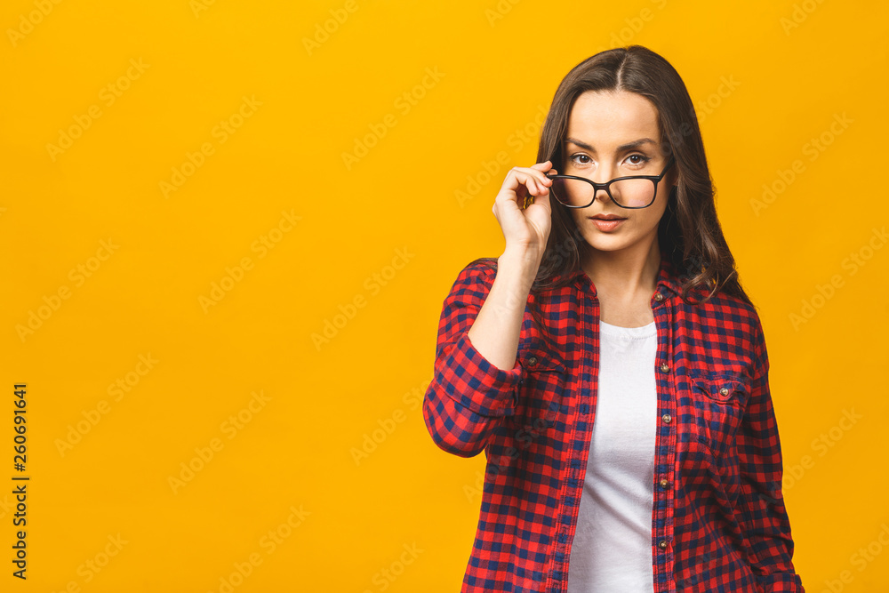 Portrait of a pretty serious woman in casual posing isolated on a yellow background.