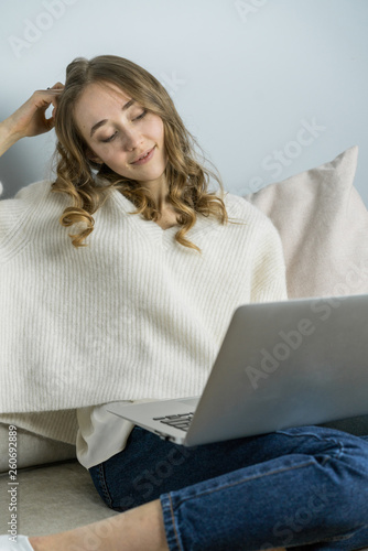 Girl sitting on sofa with laptope, hold big white mag cacao with marshmallow and listen music. Home cozy lifestile photo photo