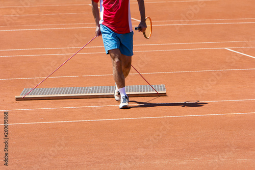 Player aligns surface tennis court, with pulling network