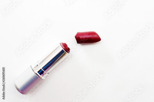 open case with broken Burgundy lipstick on white background