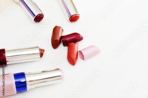 pieces of broken lipstick and open cases lie side by side on a white background