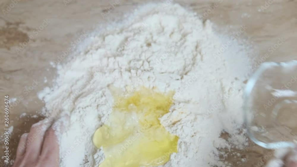 Kneading dough. Women's hands pour a broken egg into flour and knead the dough. Kneading dough. Women's hands pour a broken egg into flour and knead the dough.