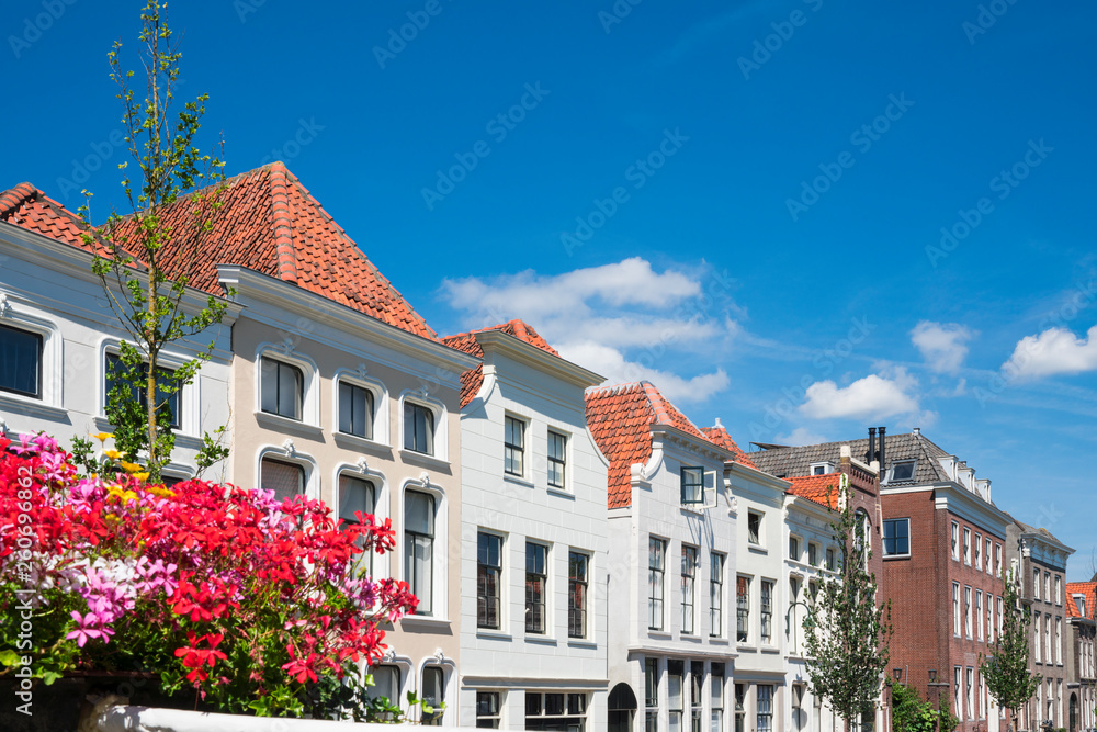 Fototapeta premium row white houses in street Turfmarkt in Gouda, The Netherlands. Against blue sky