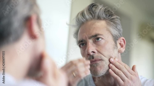 Mature man looking at himself in mirror