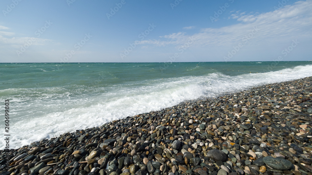Sea with small waves on a pebble beach