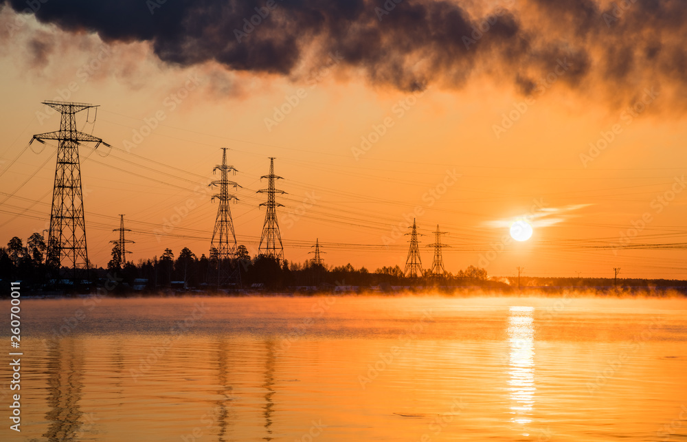 View of the power line at the shore of the lake at sunrise