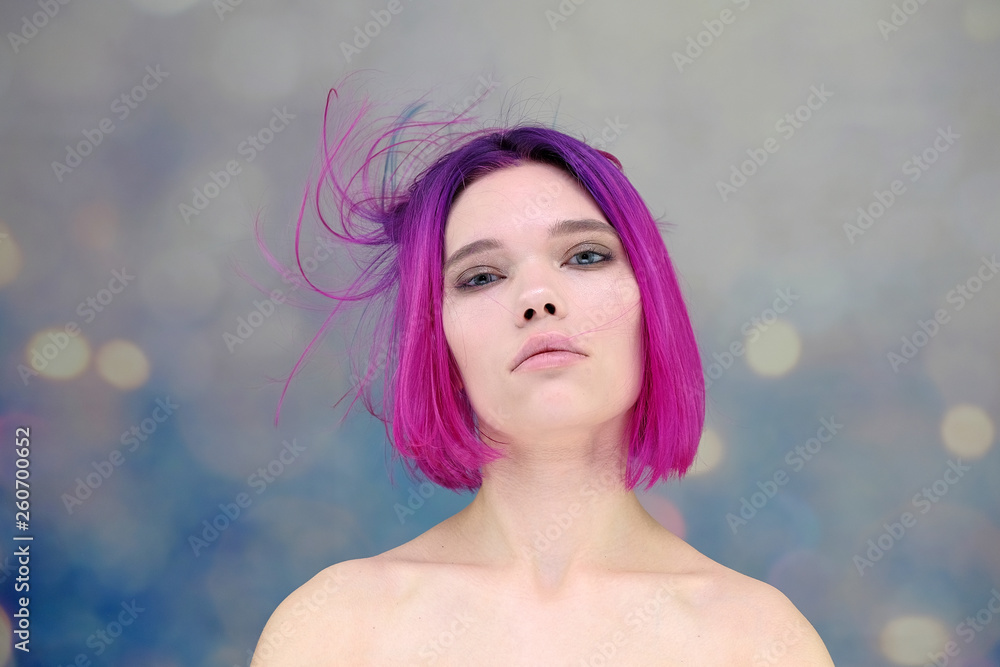 Concept Portrait of a punk girl, young woman with chic purple hair color in studio close up on a colorful background with fluttering hair.