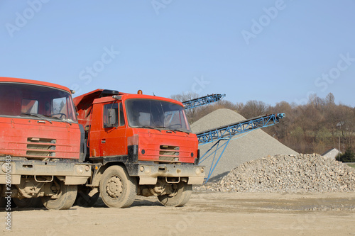 Tatra's red dump truck in the background of rubble sorting. Elements of equipment for the extraction and sorting of rubble. Production of construction materials. Metal construction for working