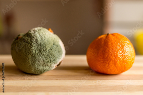Canvas Print Rotten and fresh orange on wooden background.