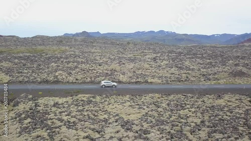 Aerial sidewards view of a car driving through vulcanic, Icelandic landscape. photo