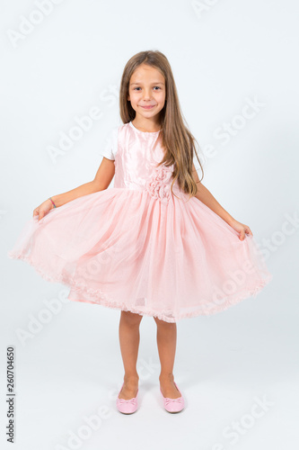 Bambina castana con capelli lunghi in abito rosa
