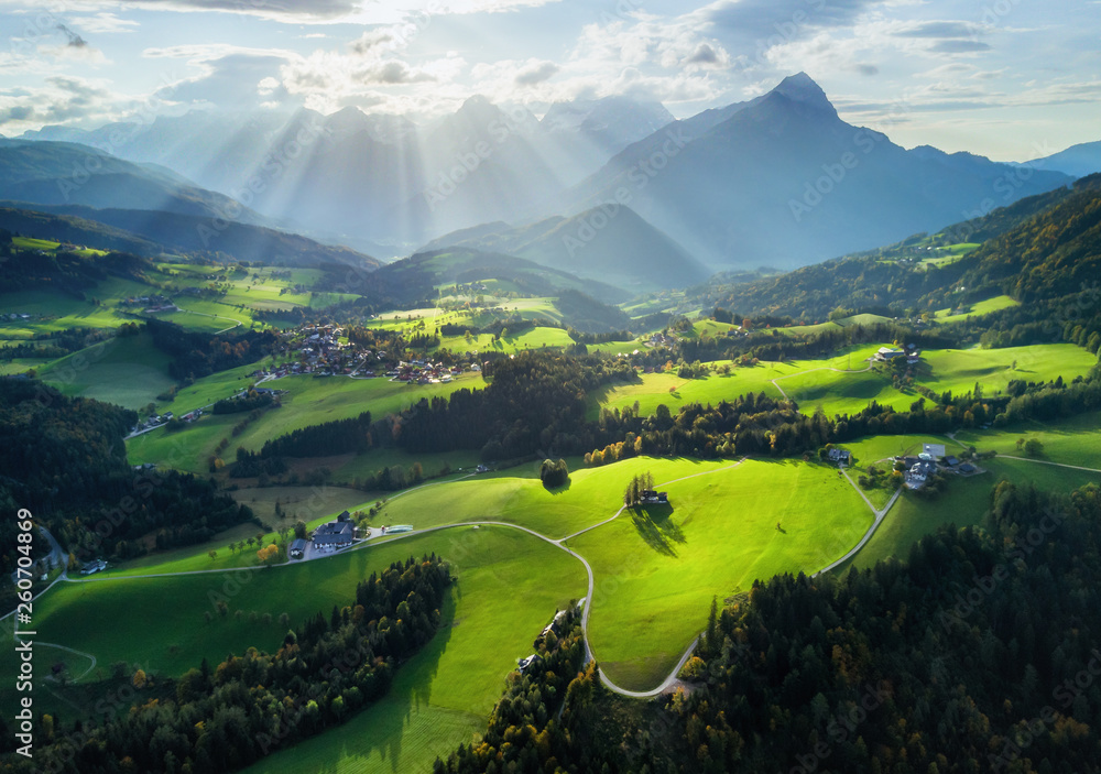 Aerial shot of sun rays above the spring green meadows - obrazy, fototapety, plakaty 