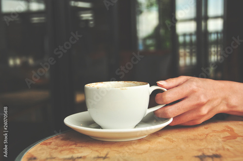 female hand holding hot coffee cup