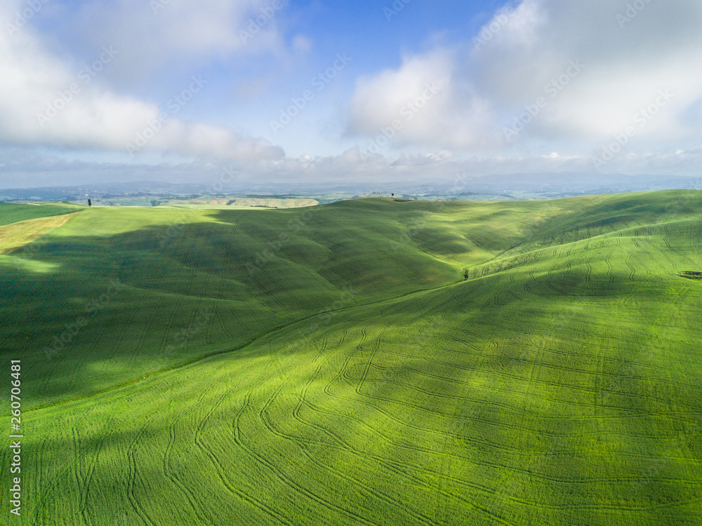 Aerial shot by drone of the green tuscan meadows at sunny spring morning