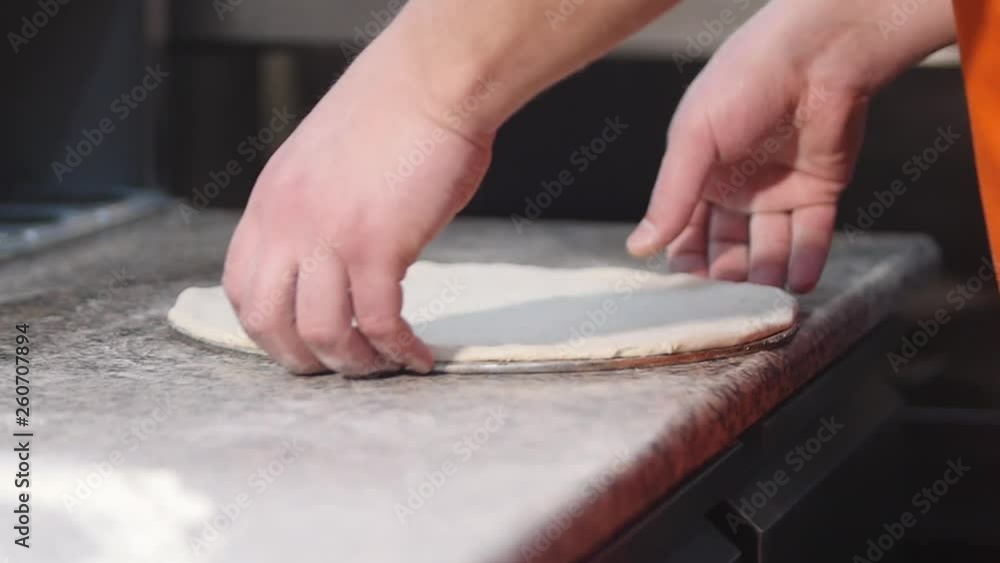 Close up hands of young pizza maker in apron preparing dough. Chef make pizza slow motion Close up hands of young pizza maker in apron preparing dough. Chef make pizza slow motion
