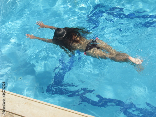 girl swims in the pool under the scorching sun