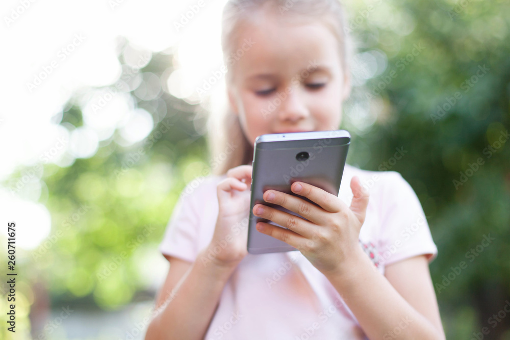 Kid is using mobile phone. Child is smiling and looking at screen of devices. Little girl is playing in children digital games at green background. Kid is using mobile phone. Child is smiling and looking at screen of devices. Little girl is playing in children digital games at green background.