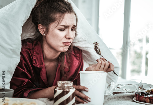 Depressed woman eating a lot of sweets