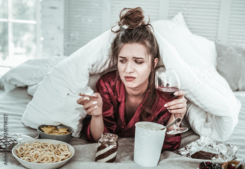 Canvas Print Depressed young woman eating a lot alone