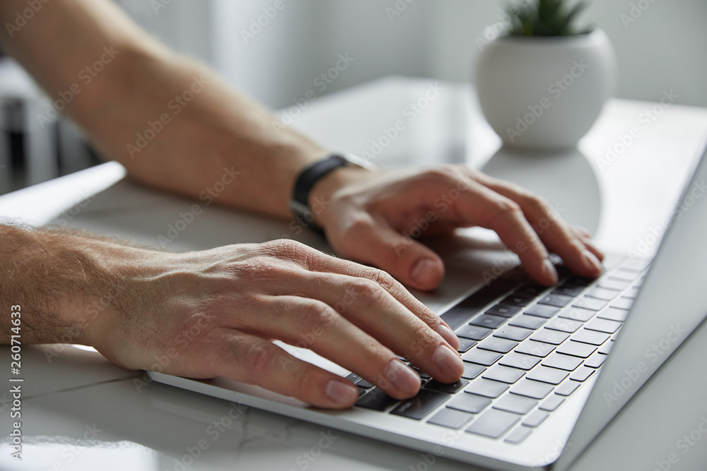 cropped view of man using laptop with black keypad on white marble table cropped view of man using laptop with black keypad on white marble table