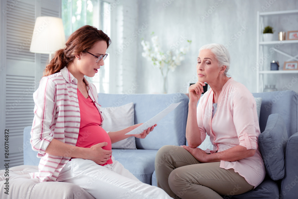 Mother listening to pregnant daughter reading prescription of doctor