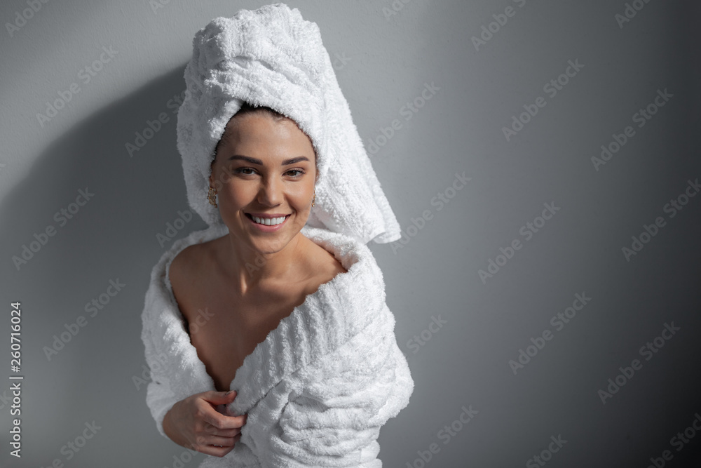 Obraz premium Attractive girl wearing white towel on head and white bath robe, smiling