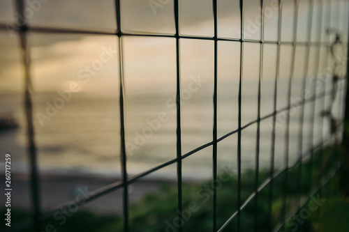 metal mesh fence. sea at sunset behind the net. restraint of liberty