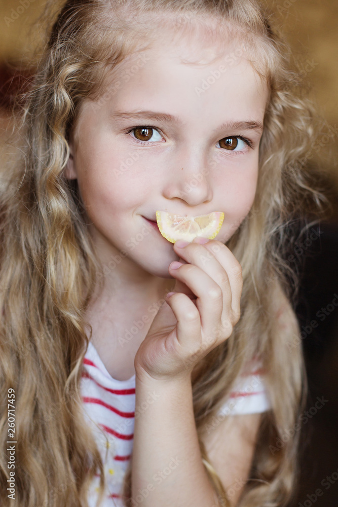 Portrait of a charming little girl with a slice of lemon