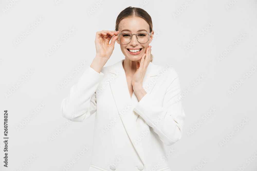 Photo of successful businesswoman 20s wearing elegant jacket smiling at camera and holding eyeglasses Photo of successful businesswoman 20s wearing elegant jacket smiling at camera and holding eyeglasses