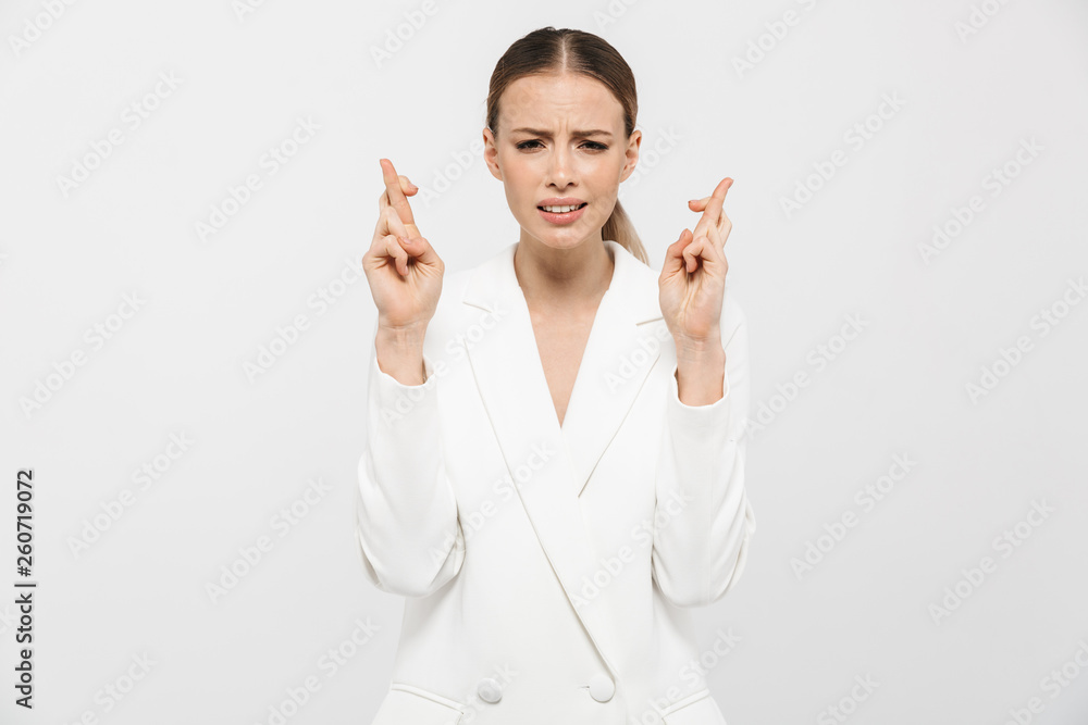 Photo of concentrated businesswoman 20s wearing elegant jacket wishing luck with keeping fingers crossed