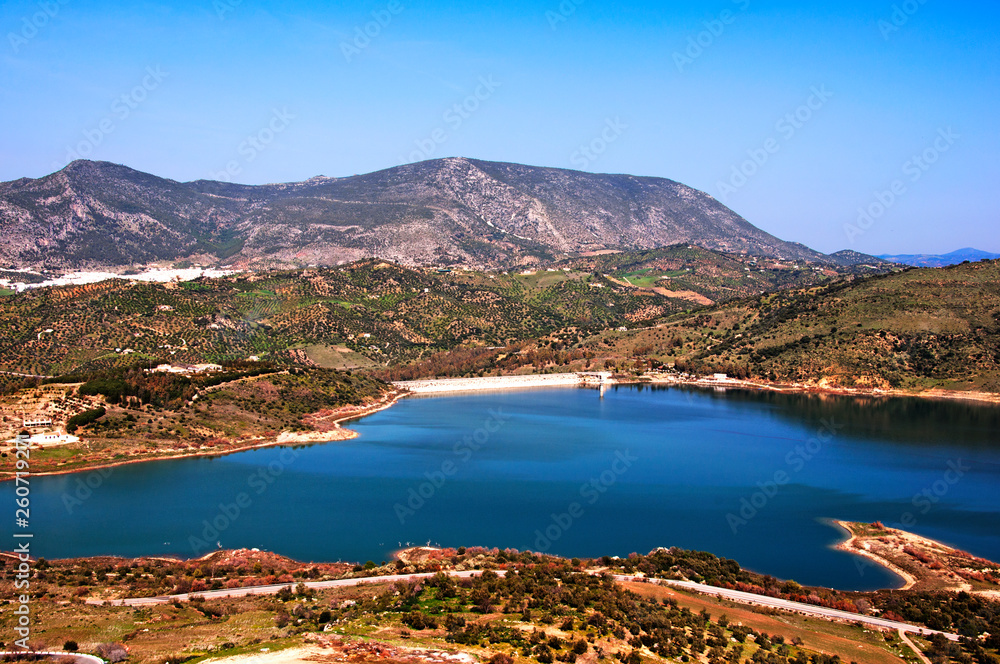 Big blue lake surrounded by mountains, olive trees, springtime