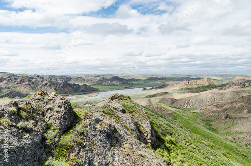 The river flows among the rocks and mountains in the green steppes of Kazakhstan. © clubclose