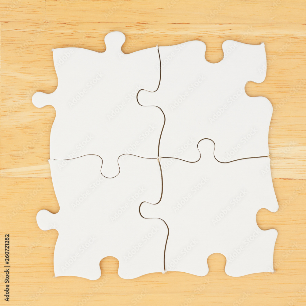 Four blank puzzle pieces on textured desk wood background Four blank puzzle pieces on textured desk wood background