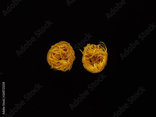 Italian noodle pasta uncooked over black background in studio from top view