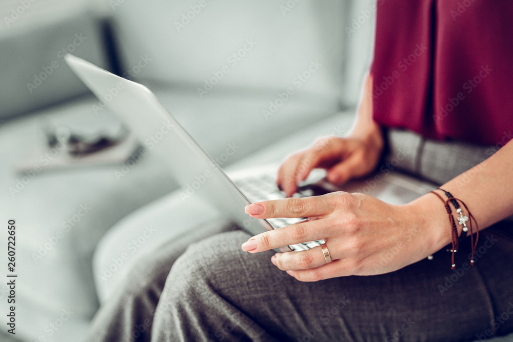 Woman wearing red blouse and bracelets on her hand using laptop