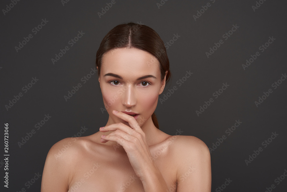 Beautiful girl with natural makeup keeping hand near her lips Beautiful girl with natural makeup keeping hand near her lips