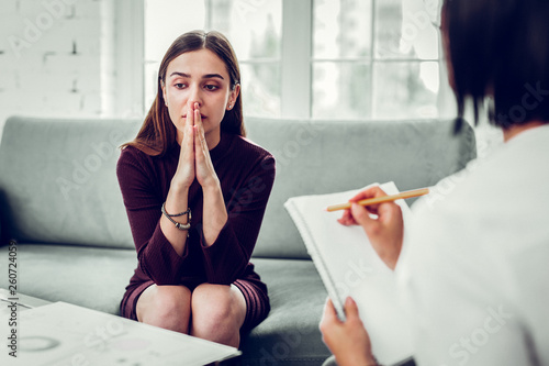 Young woman feeling thoughtful sharing problems with psychologist photo