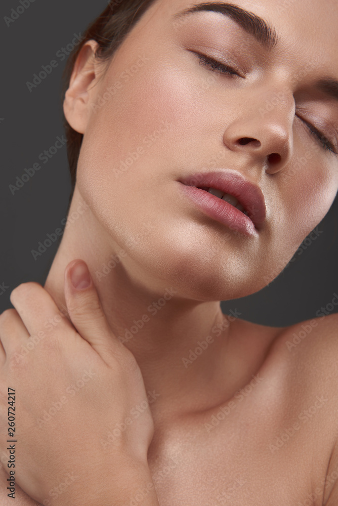 Beautiful young woman with closed eyes touching her neck Beautiful young woman with closed eyes touching her neck
