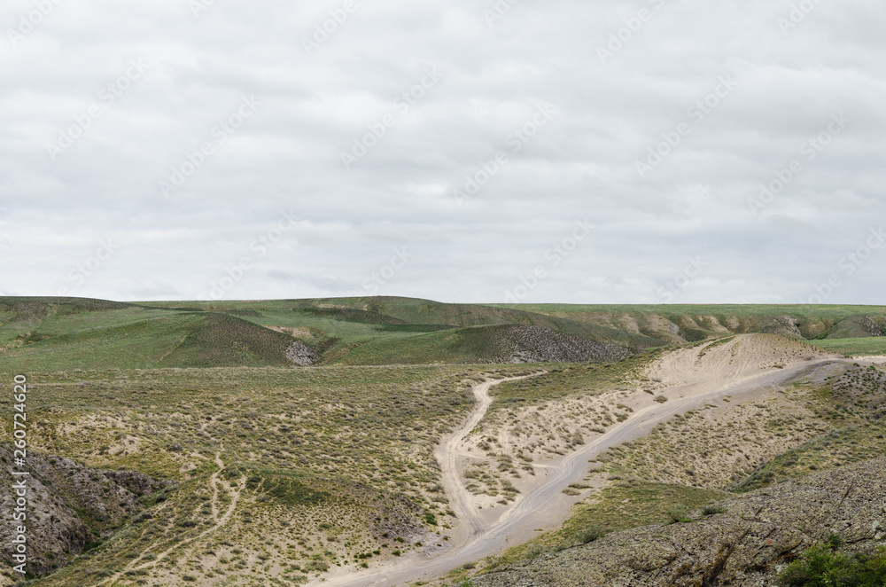 Automobile dirt and dusty roads among green hills and rocks in the mountainous region of Kazakhstan. Automobile dirt and dusty roads among green hills and rocks in the mountainous region of Kazakhstan.