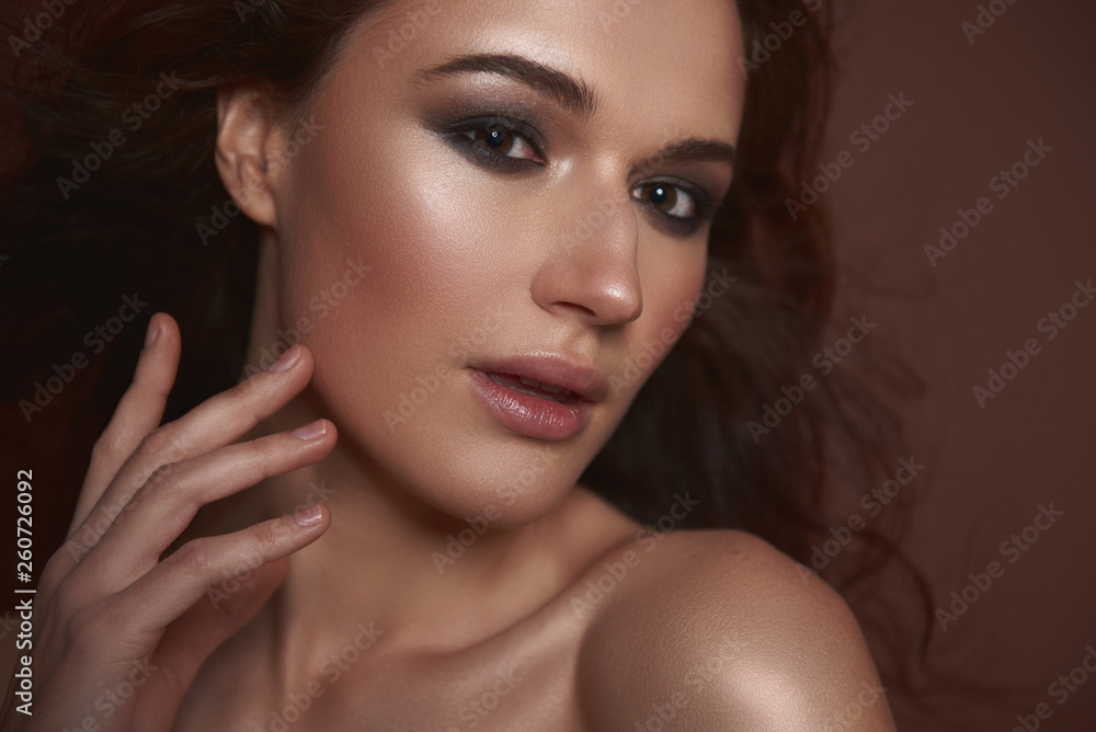 Beautiful young woman with smokey eyes makeup holding hand near face Beautiful young woman with smokey eyes makeup holding hand near face