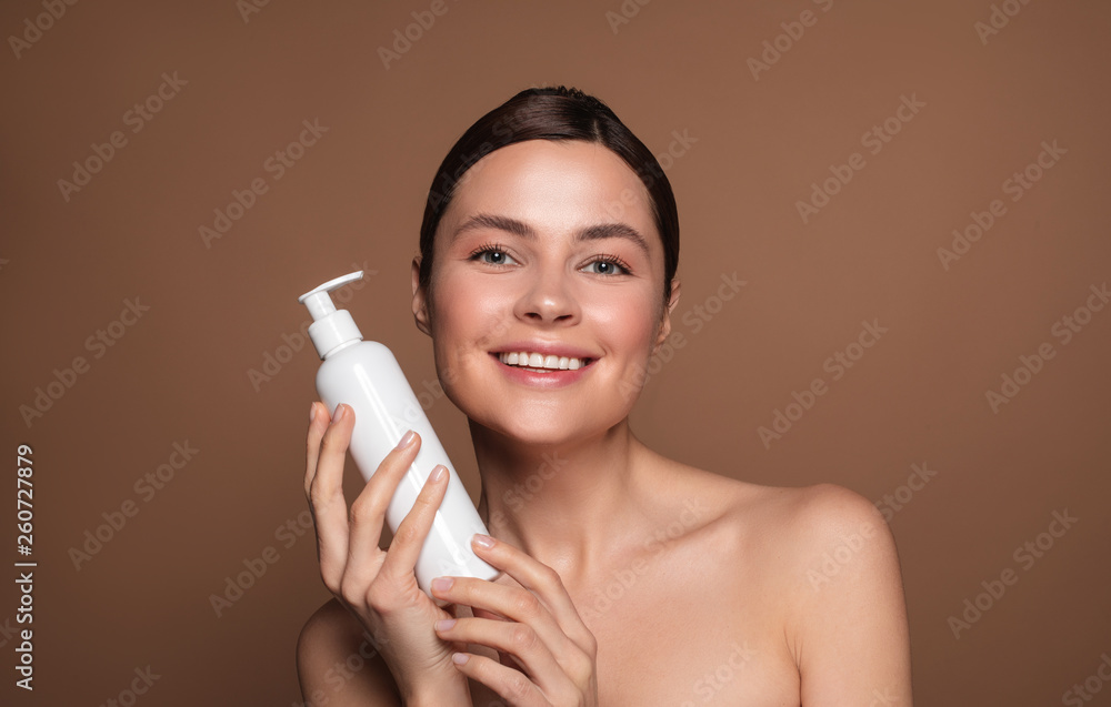 Woman with bare shoulders holding white bottle with dispenser Woman with bare shoulders holding white bottle with dispenser