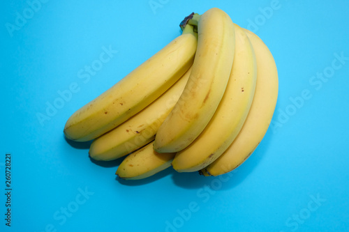 Pile of ripe bananas stack on a blue background, top view