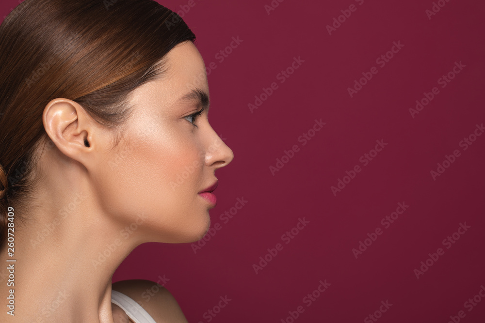 Side view of the woman looking away on the maroon background Side view of the woman looking away on the maroon background