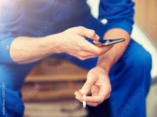 car service  repair  maintenance and people concept - auto mechanic smoking cigarette at workshop