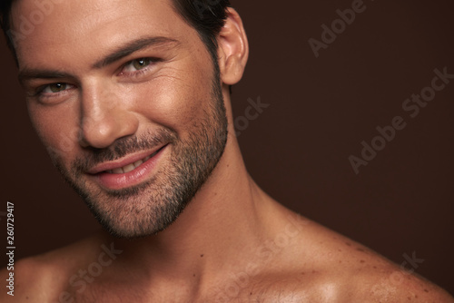 Smiling attractive young man isolated on brown